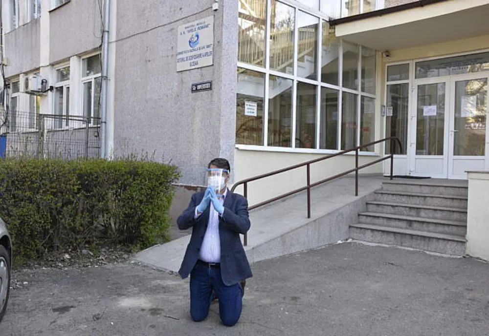 Daniel Drăgoi în genunchi în fața instituției, sursă foto Suceava News Online